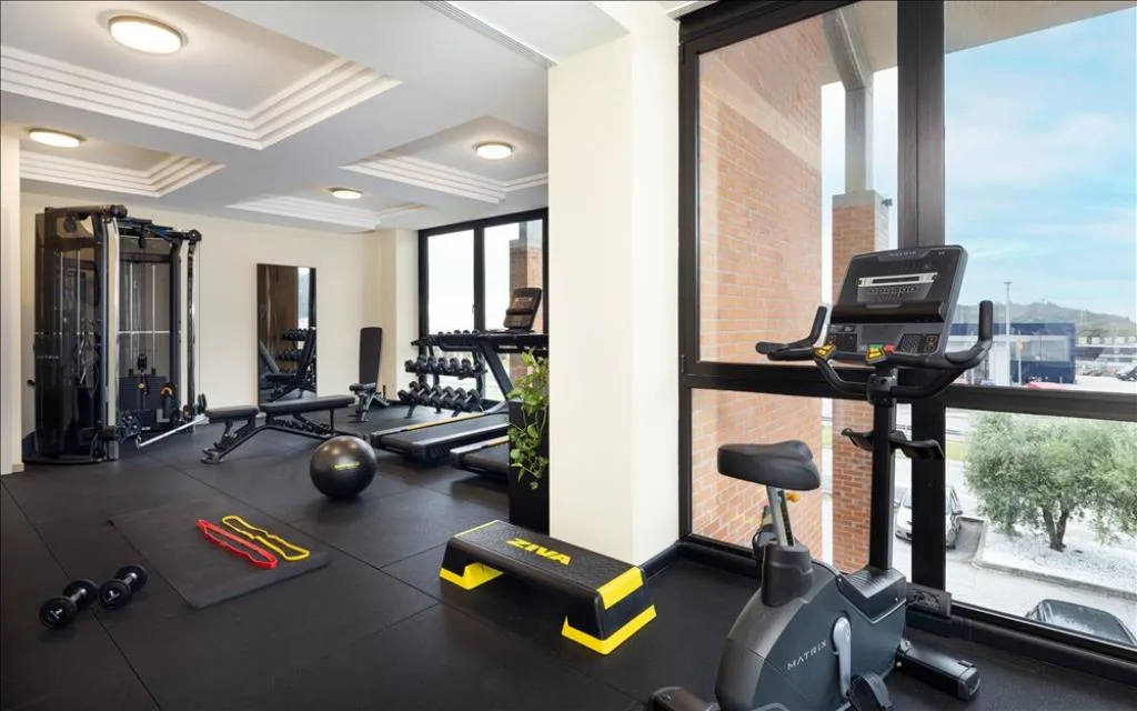 Sala fitness con attrezzi per allenamento, cyclette e grandi vetrate
