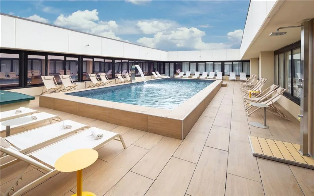 Piscina esterna su terrazza con lettini, cascata d'acqua e cielo azzurro