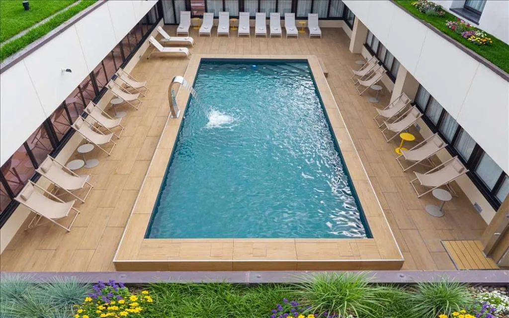 Vista dall'alto della piscina esterna con lettini, giochi d'acqua e aiuole fiorite