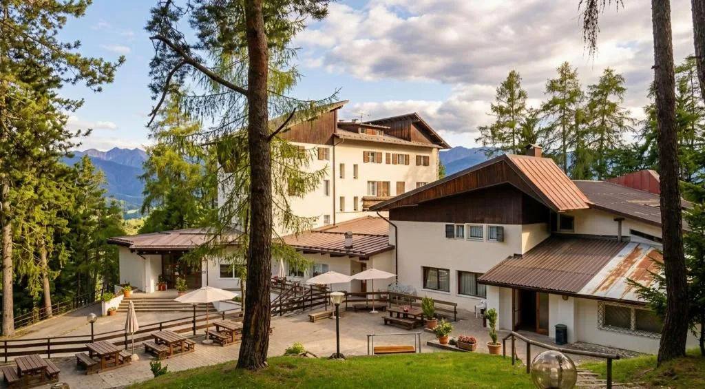 Vista estiva dell'hotel con terrazza, tavoli e panorama sulle montagne circostanti