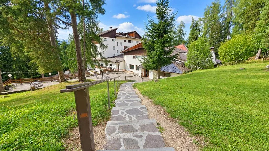 Sentiero in pietra con ringhiera tra prati verdi che conduce all'hotel in estate