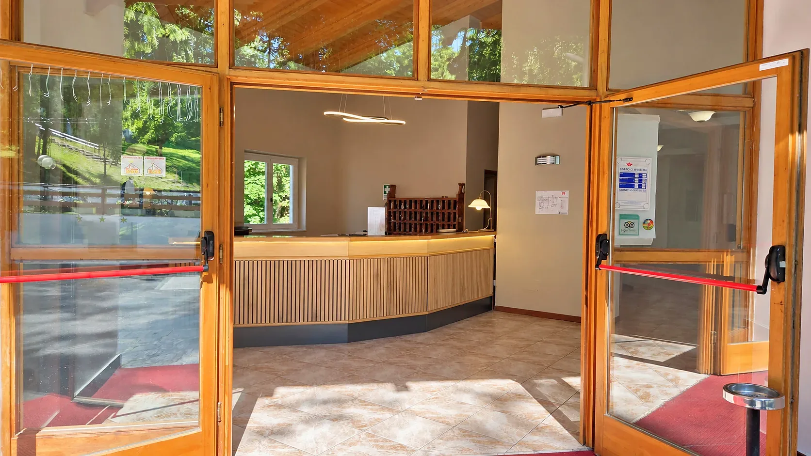 Reception dell'hotel con bancone in legno vista attraverso le porte d'ingresso