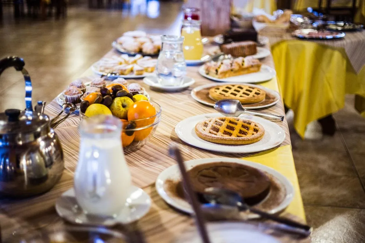Dettaglio del buffet della colazione con crostate, frutta, latte e succhi