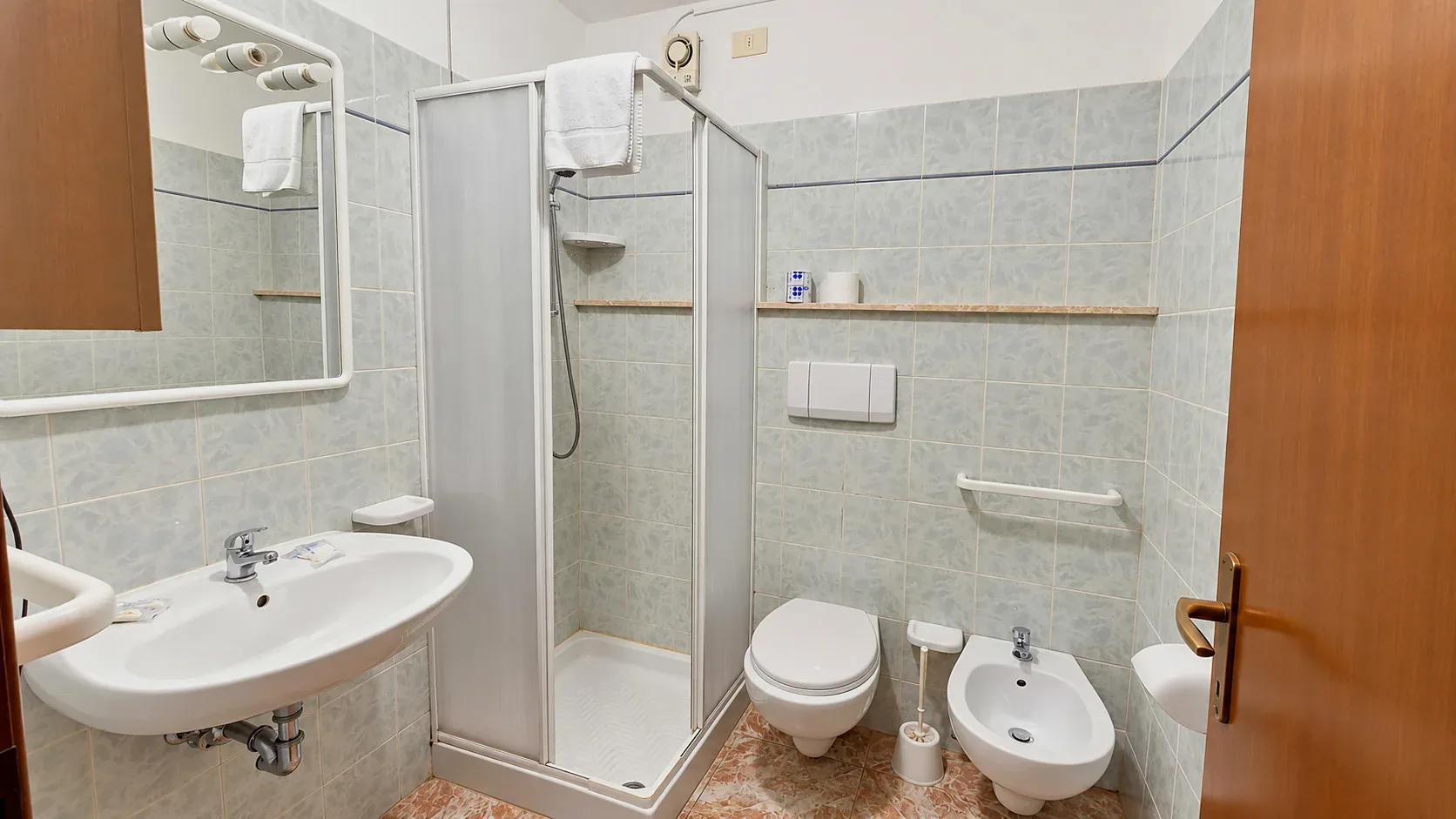 Bagno con doccia, lavabo, WC e bidet con piastrelle chiare