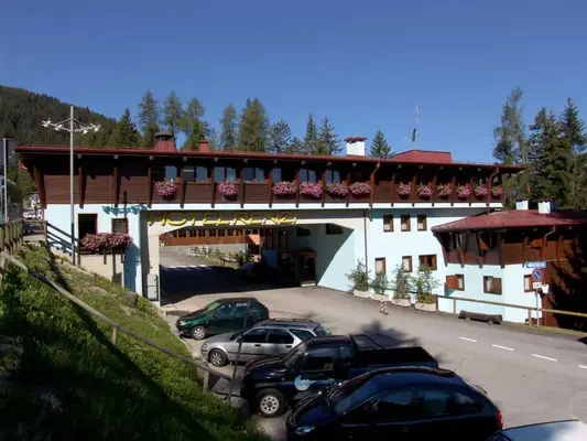 Facciata dell'Hotel Renzi con parcheggio e bosco di montagna sul retro