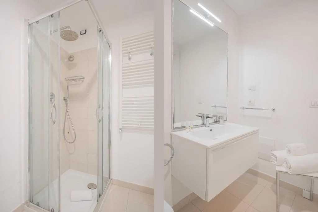 Bagno moderno bianco con doccia in vetro, lavabo e specchio illuminato
