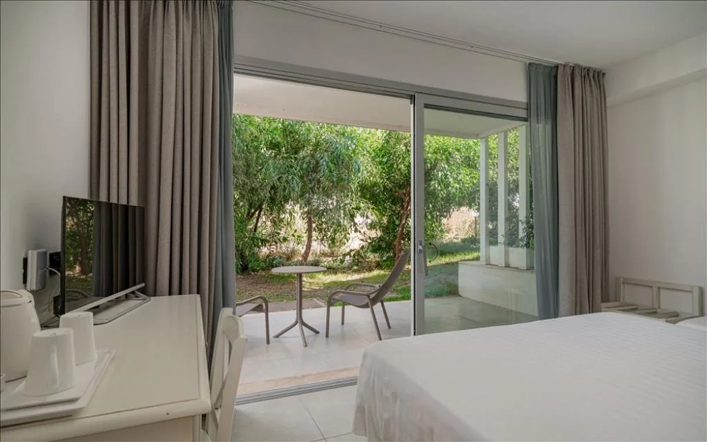 Camera con accesso a terrazza e giardino verde attraverso ampia vetrata
