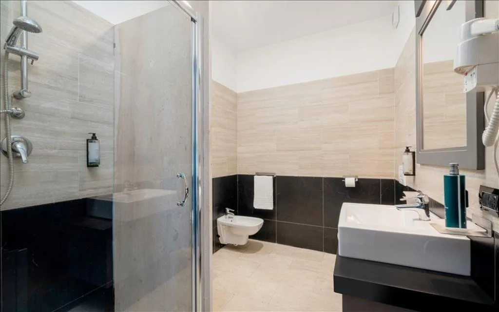 Bagno moderno con doccia, lavabo squadrato e piastrelle beige e nere