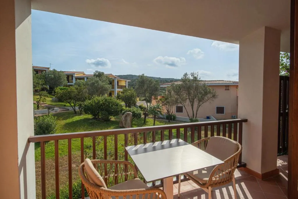 Balcone con tavolino e sedie con vista sul giardino e gli alberi del resort