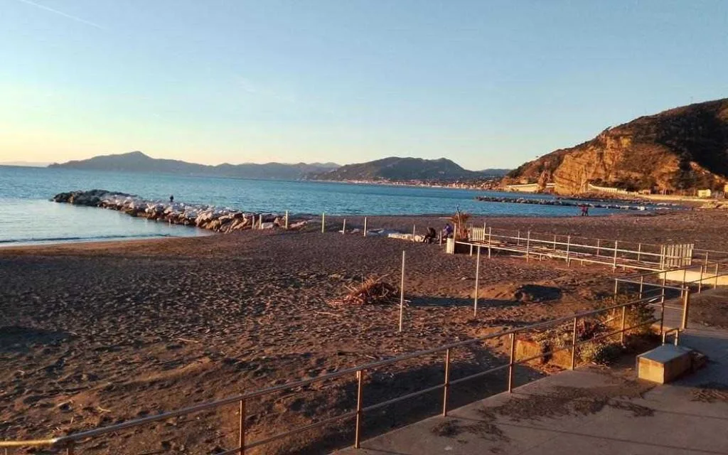 Spiaggia sabbiosa con frangiflutti e promontori al tramonto lungo la costa