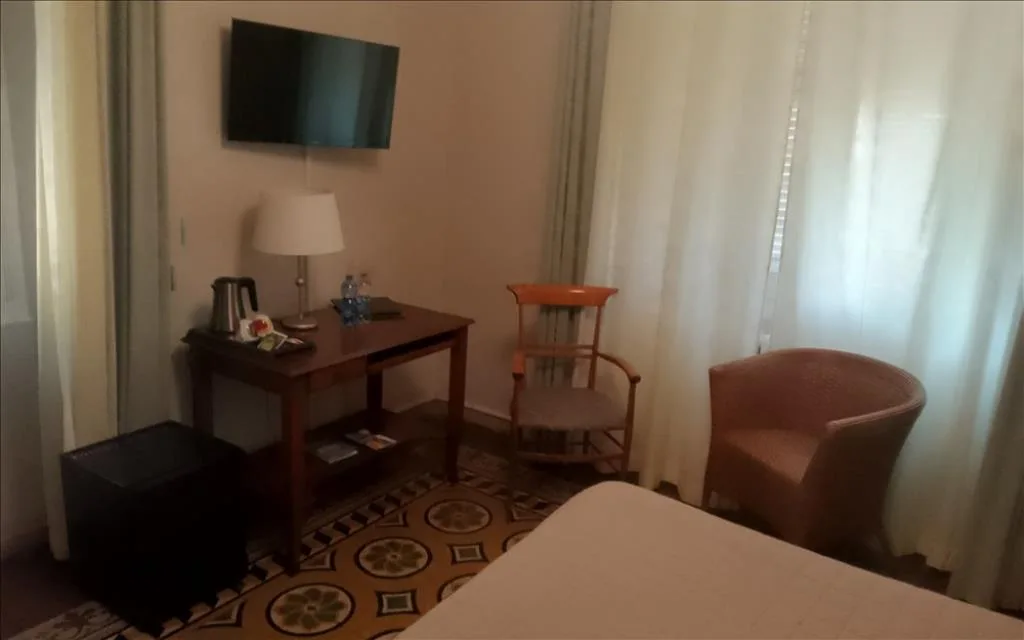Camera con TV a parete, scrivania in legno, poltrona e pavimento decorato