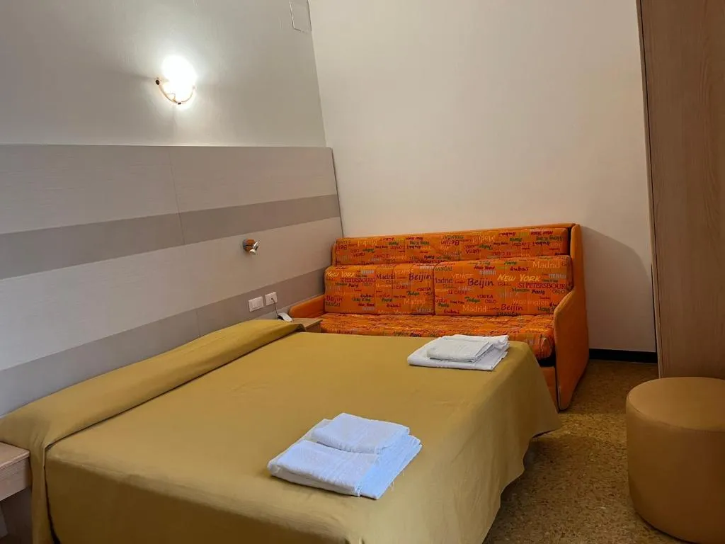 Camera con letto matrimoniale, divano arancione e applique a parete