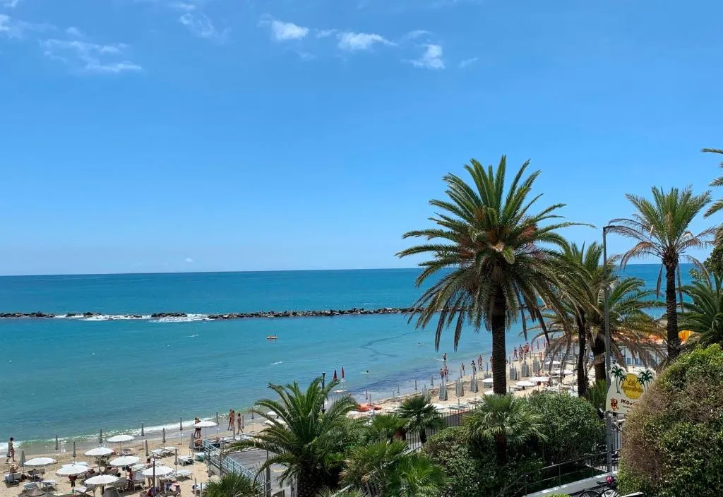 Vista sulla spiaggia con palme, ombrelloni e mare turchese in giornata di sole