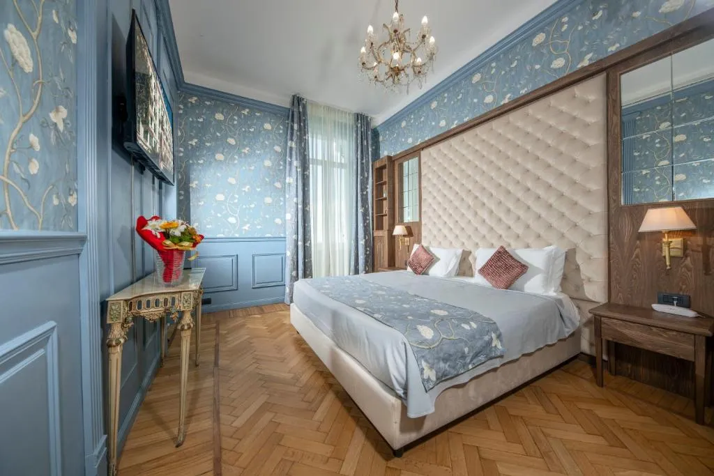 Camera di lusso con carta da parati floreale blu, lampadario di cristallo e testiera capitonné