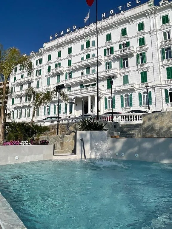 Piscina esterna con idromassaggio davanti alla facciata bianca del Grand Hotel