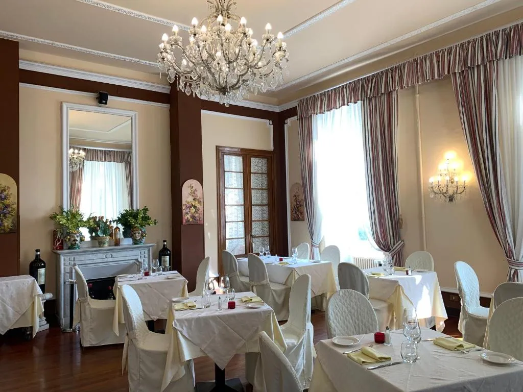 Sala da pranzo raffinata con lampadario di cristallo, tavoli apparecchiati e camino
