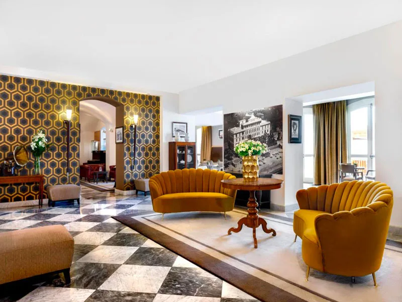 Elegante hall dell'hotel con poltrone gialle e pavimento in marmo a scacchi
