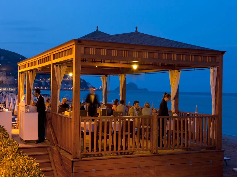 Gazebo ristorante sulla spiaggia illuminato al tramonto con vista mare