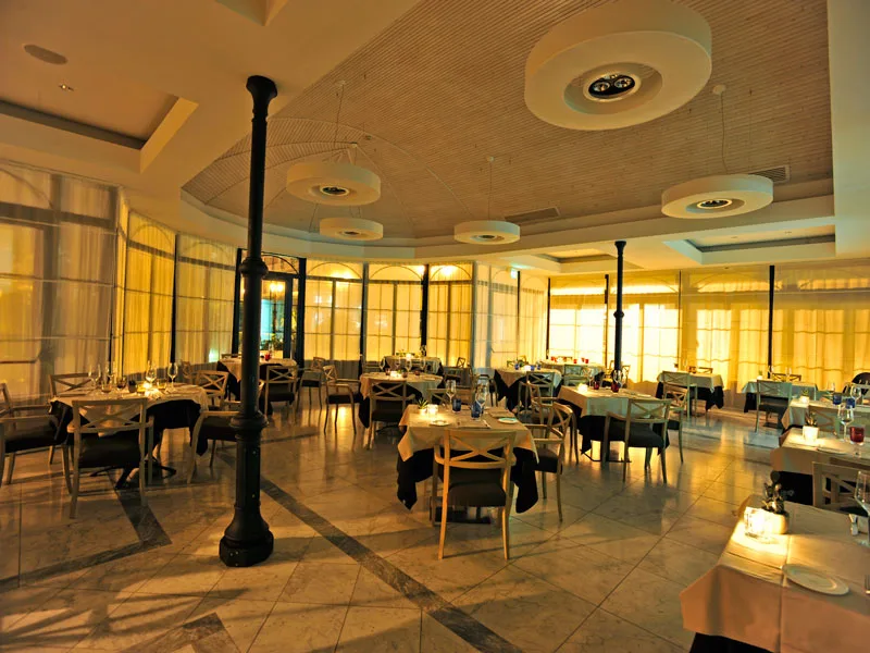 Sala ristorante interna con tavoli apparecchiati e luci soffuse