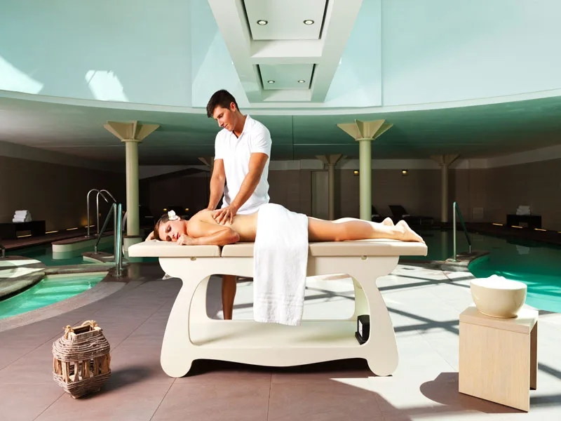 Trattamento di massaggio nella spa con lettino e piscine ai lati