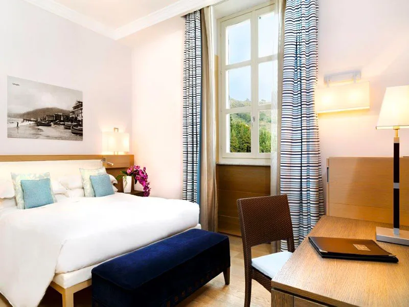 Camera elegante con letto matrimoniale, scrivania e vista sul verde