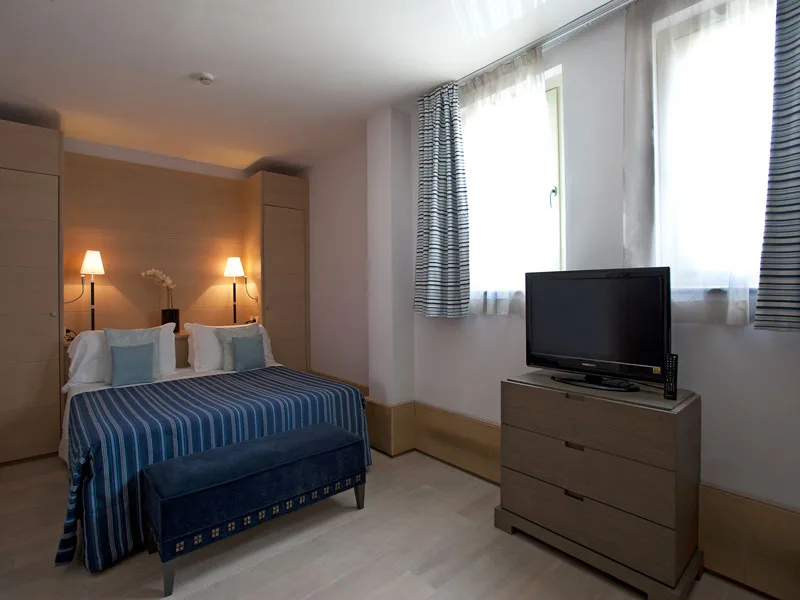 Camera con letto a righe blu, comò e televisore
