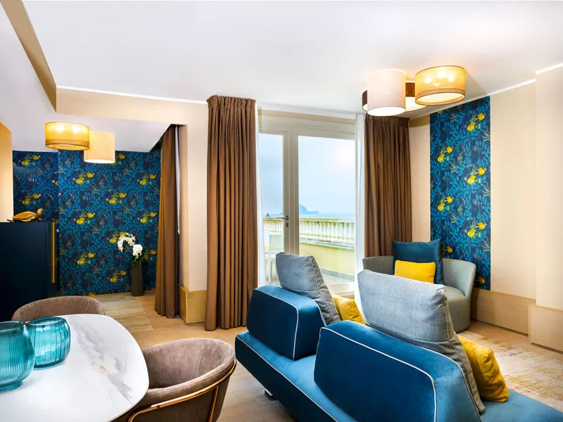 Salotto suite con divano blu e vista sul mare dalla finestra