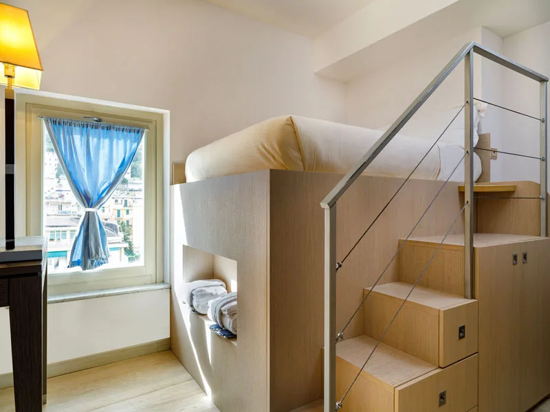 Camera con letto soppalcato e scala in legno con vista sul borgo