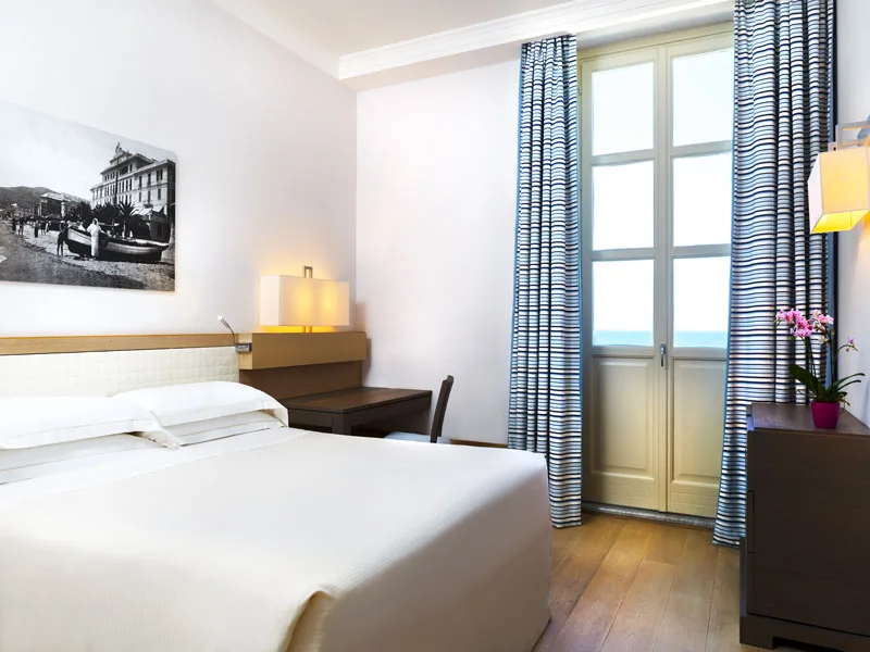 Camera luminosa con letto matrimoniale e porta finestra con vista mare