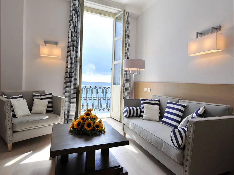 Soggiorno con divano e poltrona grigi, girasoli e balcone vista mare
