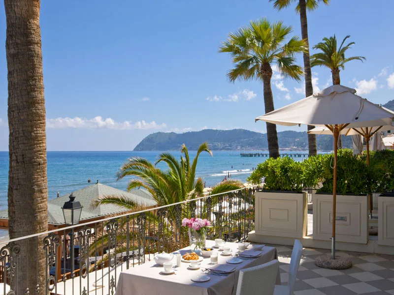 Terrazza con tavolo apparecchiato per colazione e palme vista mare