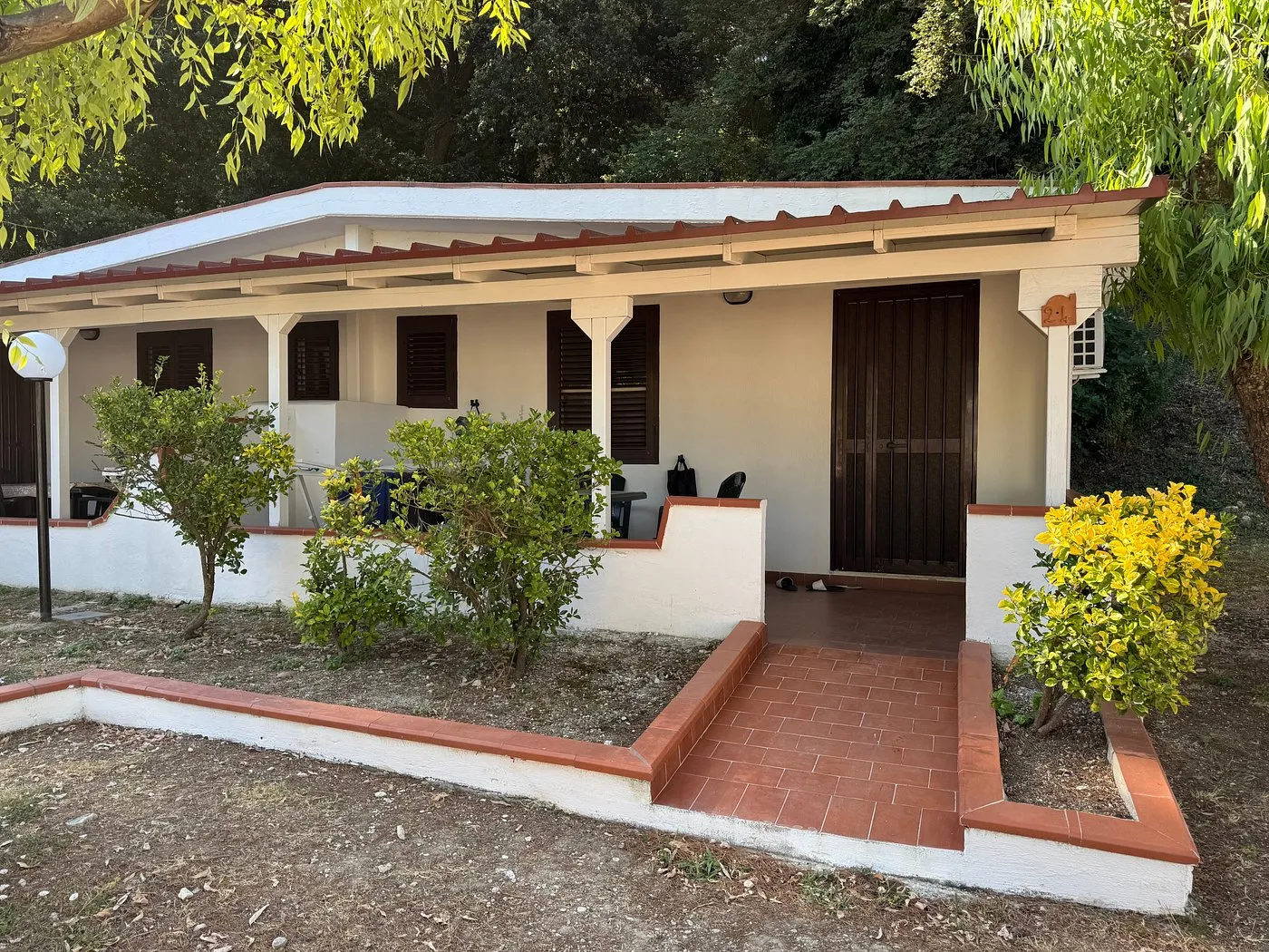 Esterno di un bungalow con veranda coperta, ingresso e piante ornamentali