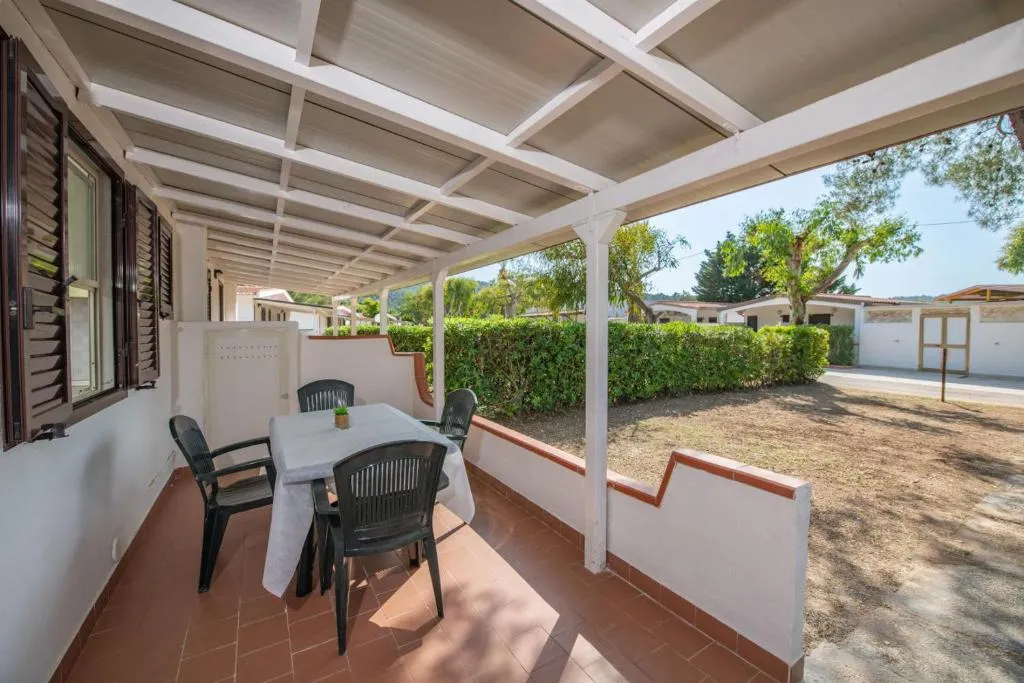 Veranda coperta con tavolo, sedie e vista sul giardino del villaggio
