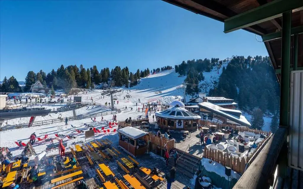 Vista dal balcone sulla terrazza affollata e sulle piste da sci in giornata soleggiata
