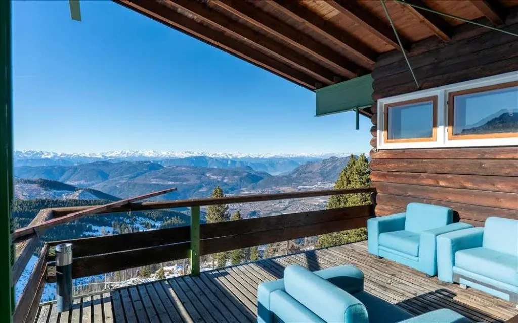 Terrazza in legno con poltrone azzurre e vista panoramica sulle Alpi