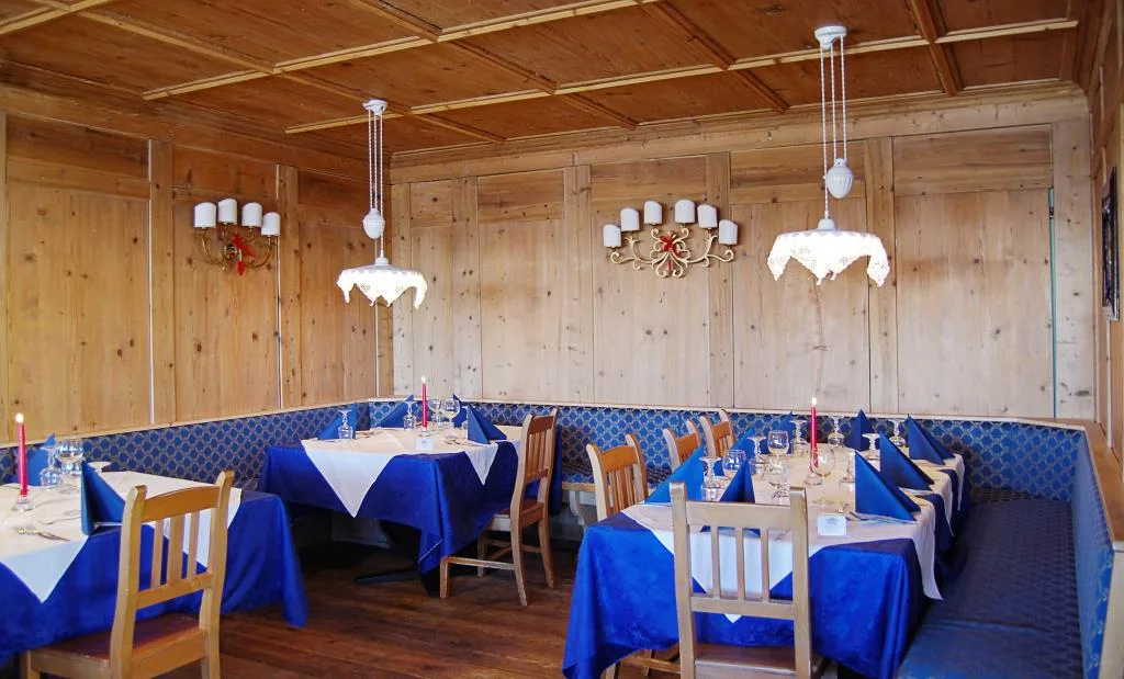 Sala ristorante rivestita in legno con tavoli apparecchiati e tovaglie blu