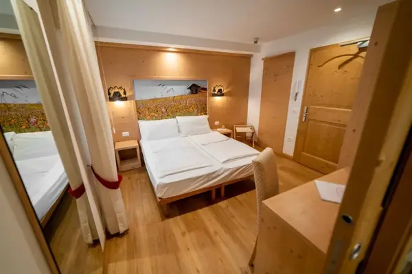 Camera matrimoniale con pareti in legno e murale di prato fiorito sopra il letto
