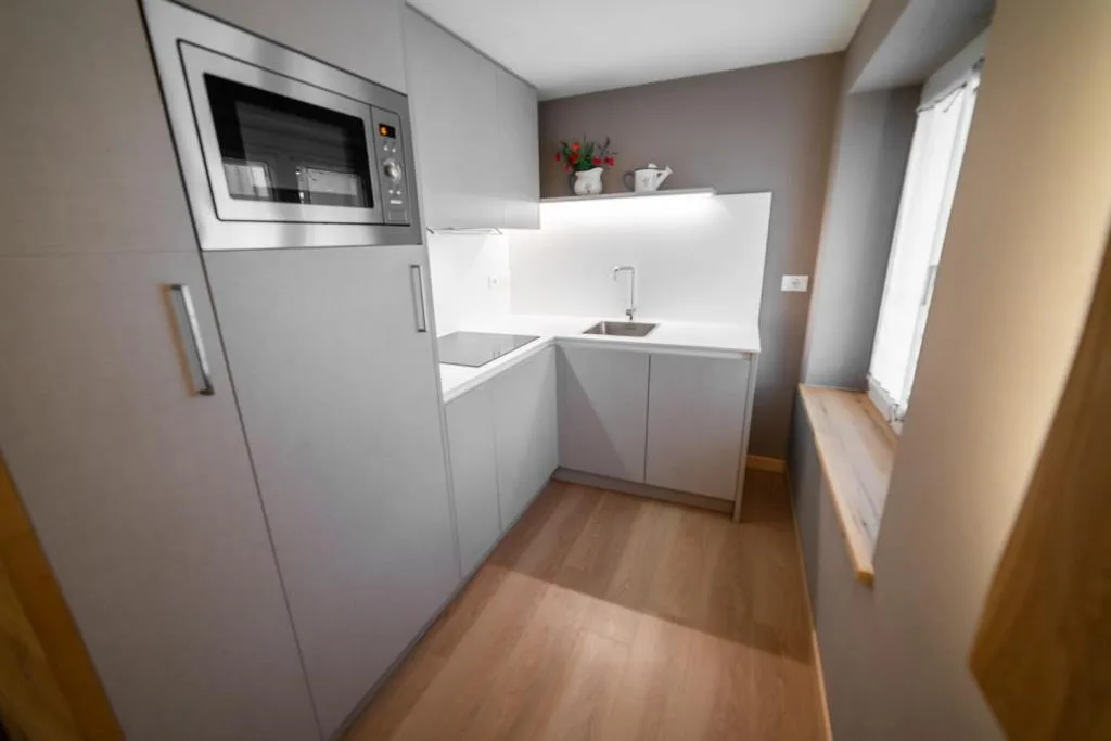 Piccola cucina moderna con mobili grigi, microonde e lavello