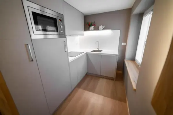 Piccola cucina moderna con mobili grigi, microonde e lavello