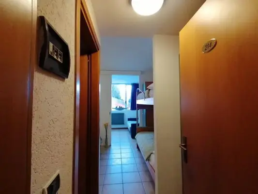 Corridoio d'ingresso di un appartamento con porta numero 214 e letto a castello