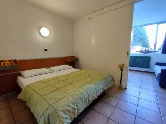 Camera con letto matrimoniale e vista sull'esterno attraverso porta scorrevole