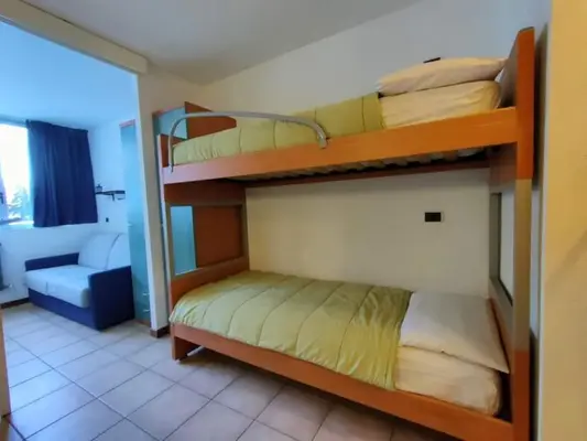 Camera con letto a castello in legno e divano bianco