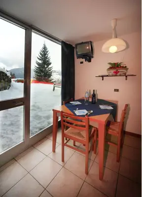 Angolo pranzo con tavolo, TV e grande finestra affacciata sulla neve