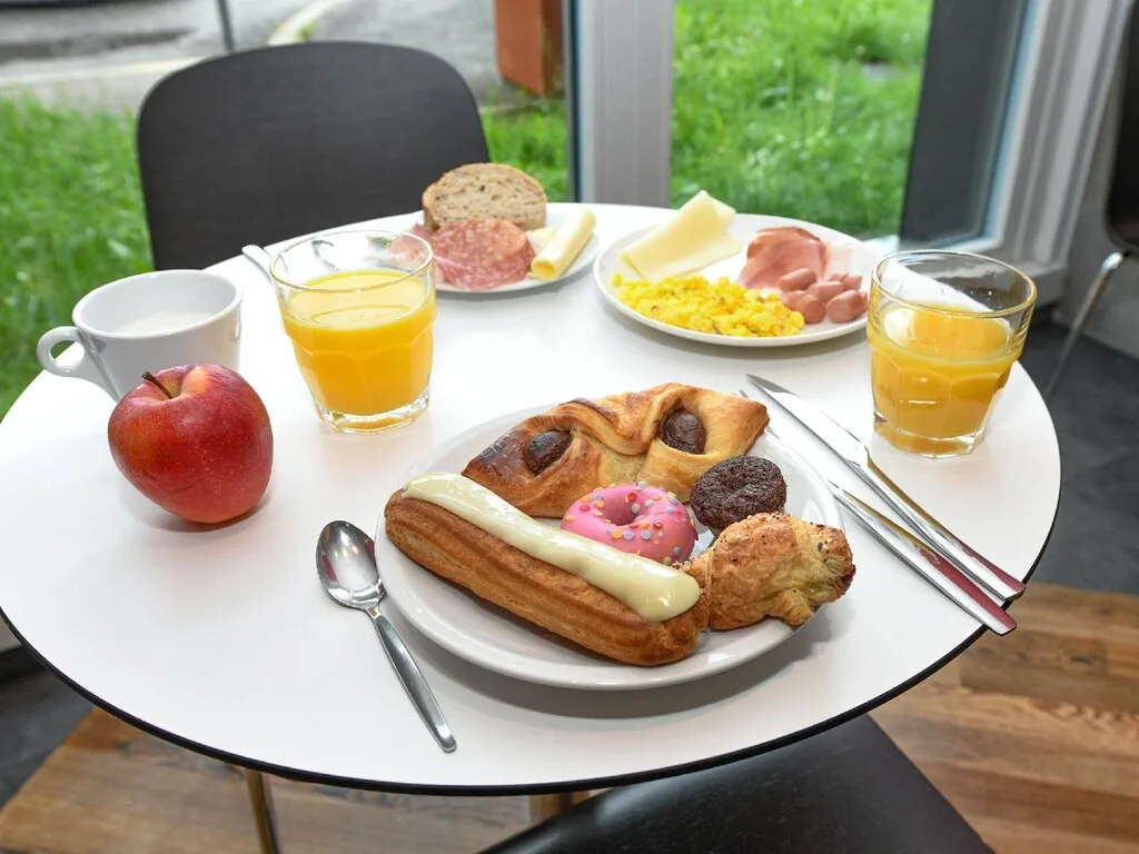 Piatto della colazione con dolci, frutta, salumi e succo d'arancia