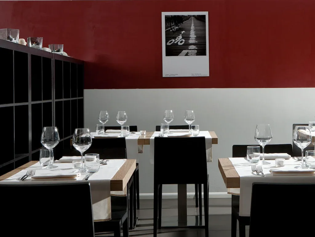 Sala ristorante con tavoli apparecchiati e parete rossa decorata