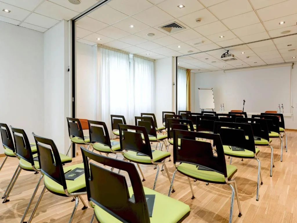 Sala meeting con sedie verdi disposte a platea e proiettore