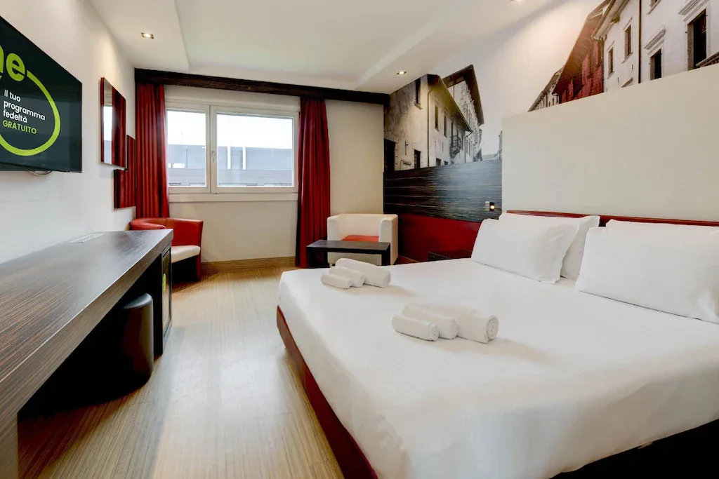 Camera matrimoniale con letto king size, tende rosse e TV a parete