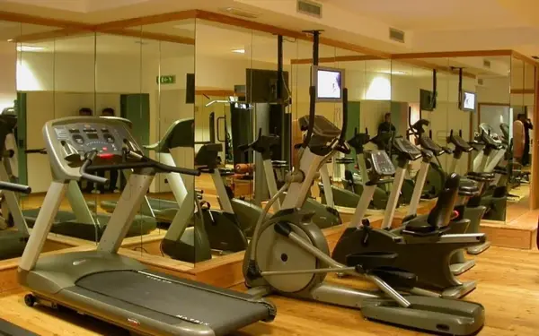 Palestra attrezzata con tapis roulant, cyclette ed ellittica davanti a pareti a specchio