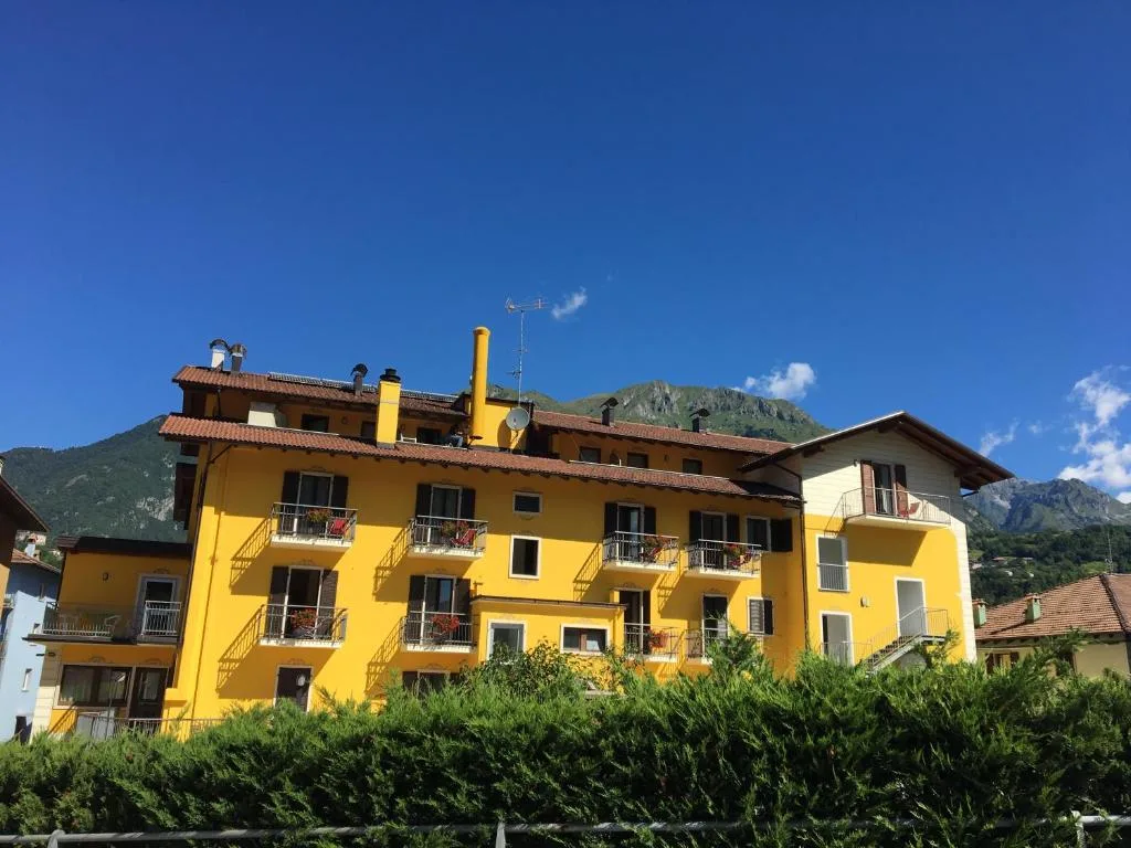 Facciata gialla di edificio con balconi e montagne sullo sfondo