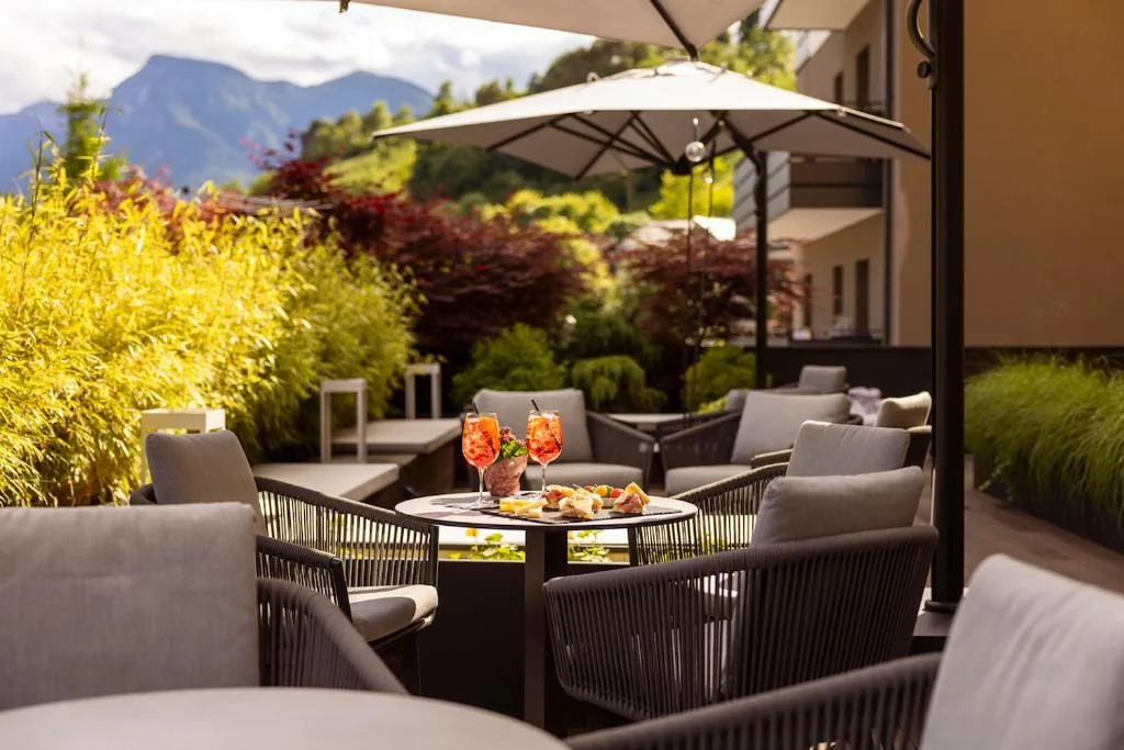 Terrazza esterna con poltrone, ombrellone e aperitivi con vista montagne